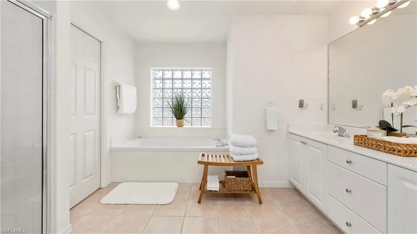 Bathroom featuring double vanity, a garden tub, light tile patterned flooring, and a shower stall