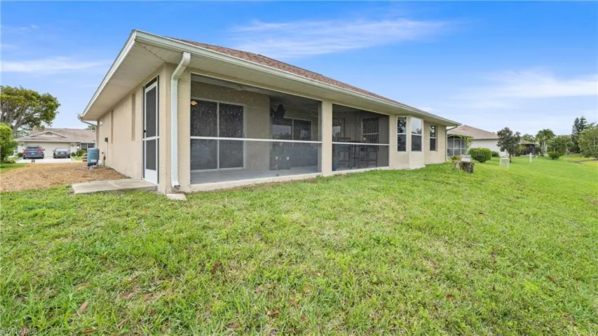 Back of property with a sunroom, stucco siding, and a yard