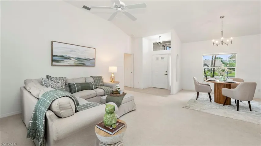 Living room with light colored carpet, a ceiling fan, vaulted ceiling, and hanging lights