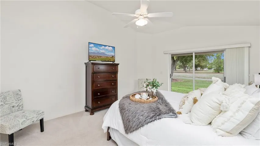 Bedroom featuring vaulted ceiling, ceiling fan, and light colored carpet