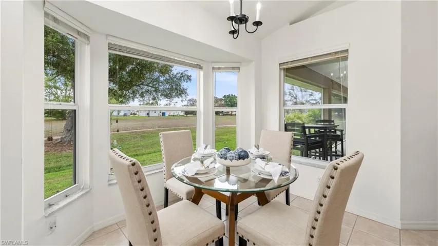 Dining space with vaulted ceiling, light tile patterned floors, and hanging lights