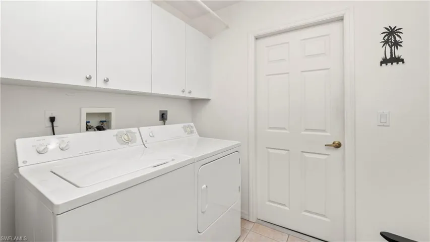 Laundry room featuring washing machine and clothes dryer, cabinet space, and light tile patterned floors