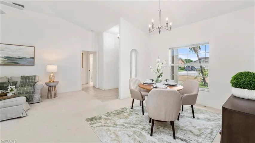 Dining room with light carpet, hanging lights, and vaulted ceiling