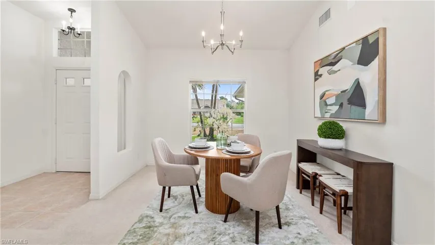 Dining room featuring hanging lights and light colored carpet