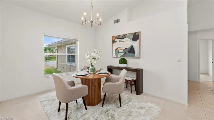Dining room with vaulted ceiling, light carpet, and suspended lighting