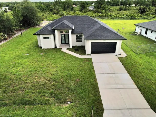 View of front facade with roof with shingles, stucco siding, concrete driveway, and a front lawn