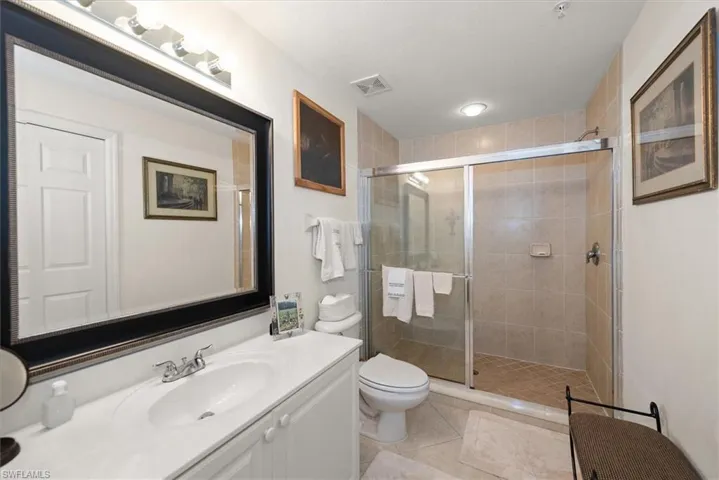 Primary bathroom featuring a walk in shower, vanity, and light diagonal pattern flooring.