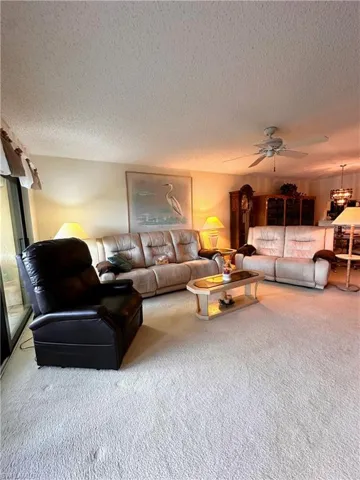 Living room with carpet floors, and a ceiling fan