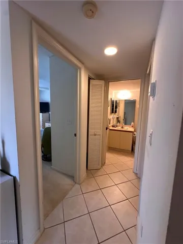 Hallway featuring light tile patterned floors and light carpet