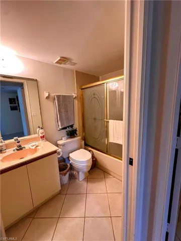 Full bathroom featuring combined bath / shower with glass door, vanity, and light tile patterned flooring
