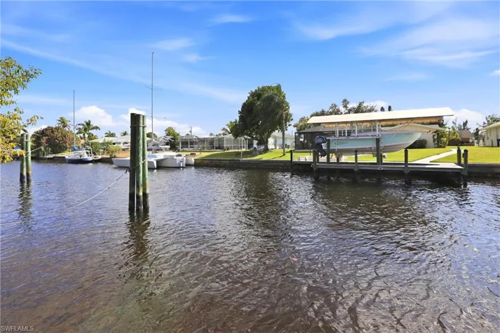 Dock area featuring a water view, boat lift, and a residential view
