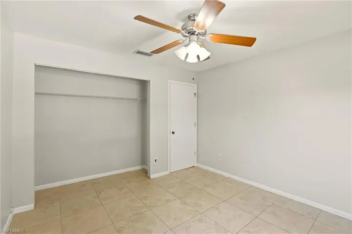 Unfurnished bedroom with ceiling fan, a closet, and light tile patterned floors