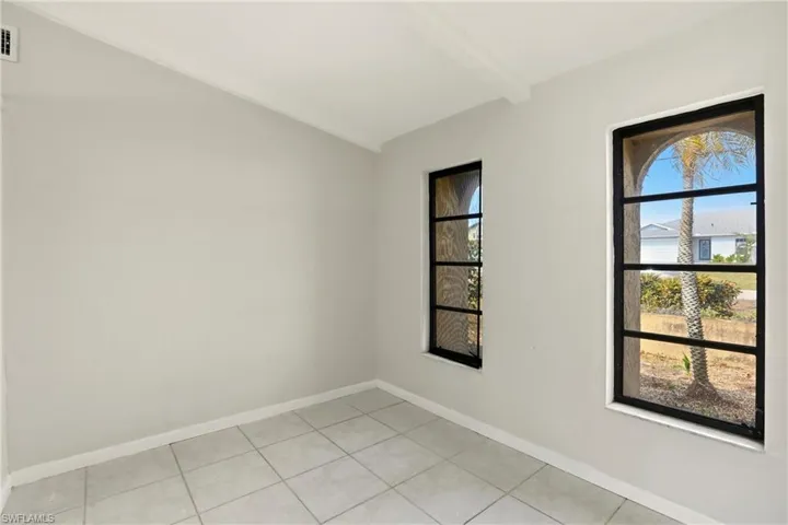 Spare room featuring baseboards and lofted ceiling with beams