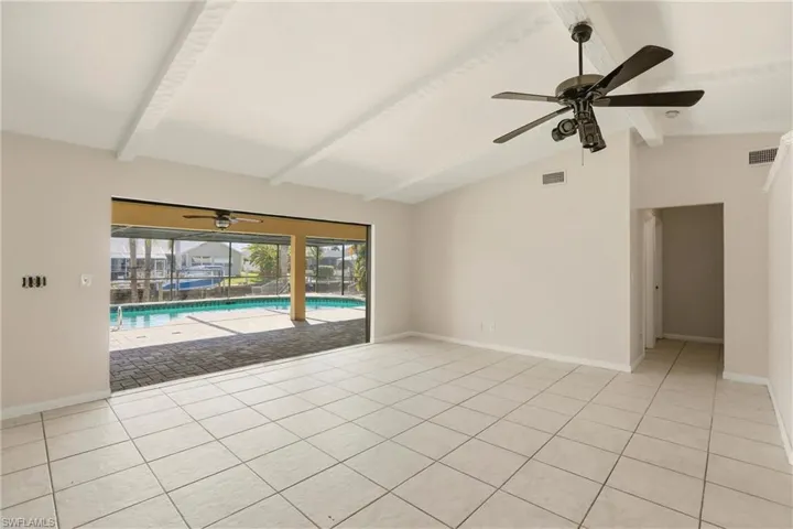 Spare room with a ceiling fan, a sunroom, vaulted ceiling, and light tile patterned flooring