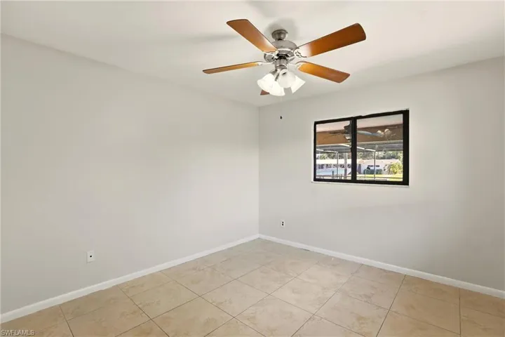 Empty room with ceiling fan and light tile patterned flooring
