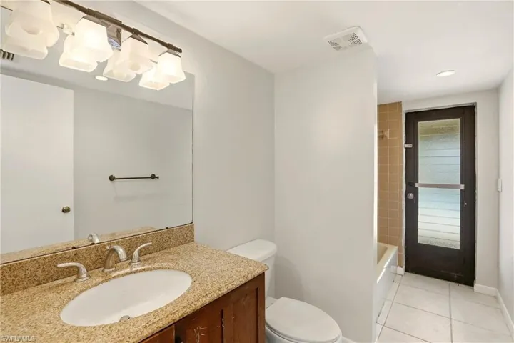 Bathroom with vanity, bathtub / shower combination, light tile patterned floors, and recessed lighting