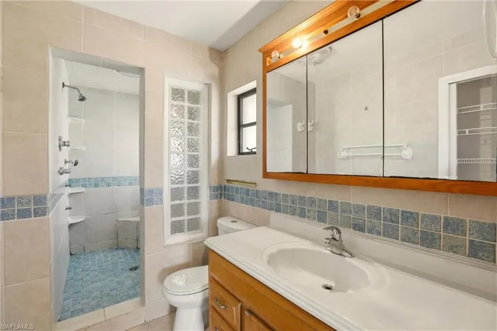 Bathroom with vanity, walk in shower, and tile walls