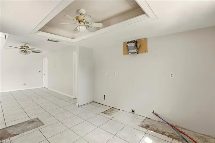 Spare room with ceiling fan, a raised ceiling, and light tile patterned floors