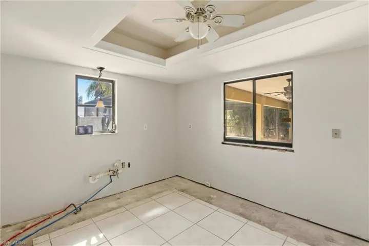 Empty room with a ceiling fan and a tray ceiling