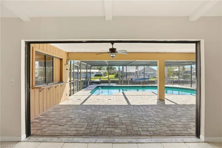 Outdoor pool with glass enclosure, a patio, and a sunroom