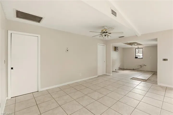 Unfurnished room with ceiling fan, light tile patterned floors, and beam ceiling