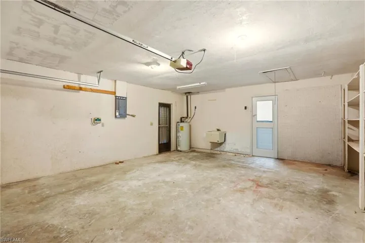 Garage featuring electric panel, water heater, and a garage door opener