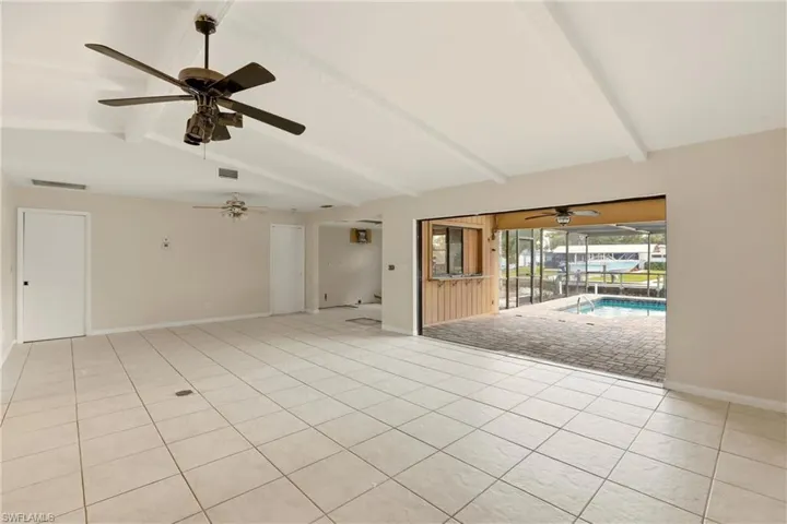 Empty room with a sunroom, vaulted ceiling with beams, ceiling fan, and light tile patterned floors
