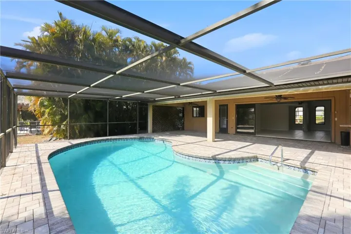 Outdoor pool with a sunroom, glass enclosure, and a patio