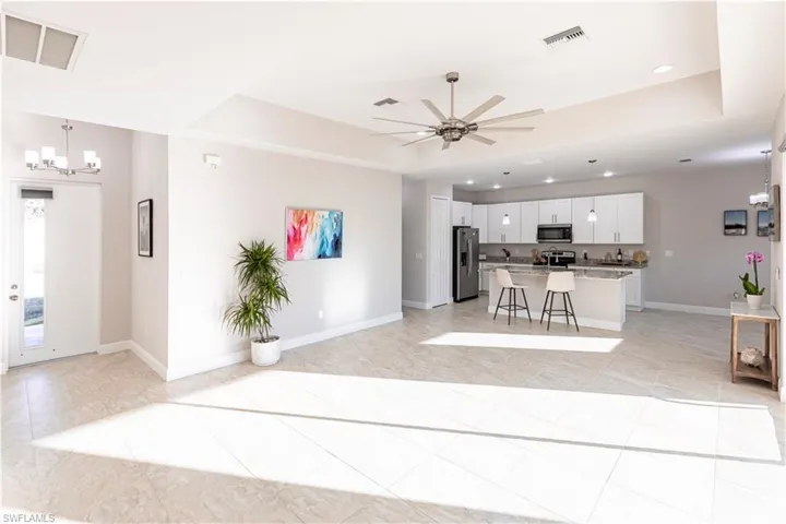 notable chandelier, white cabinetry, a breakfast bar area, a center island, and stainless steel appliances