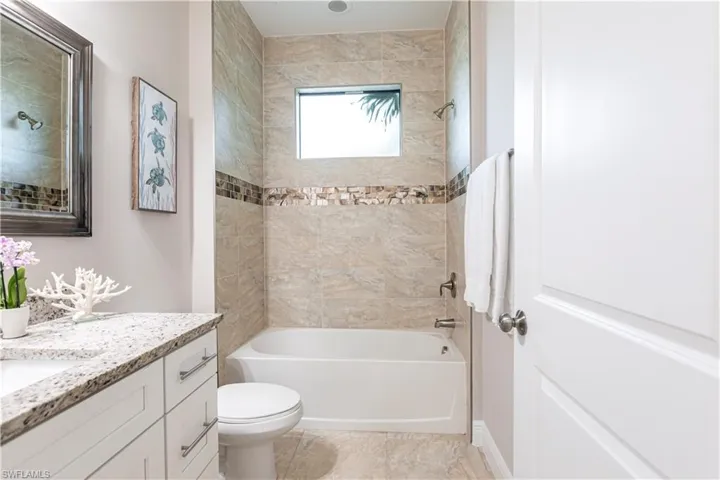 Full bathroom featuring tiled shower / bath combo, vanity, tile patterned flooring, and toilet