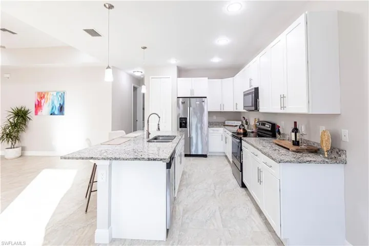 Kitchen featuring white cabinetry, sink, decorative light fixtures, and appliances with stainless steel finishes