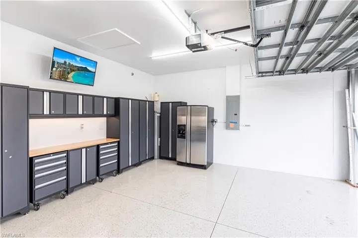 Garage featuring a garage door opener, stainless steel fridge, and electric panel