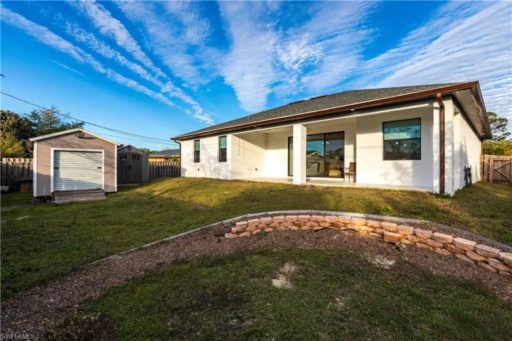 Back of house with a patio, a lawn, and a storage unit