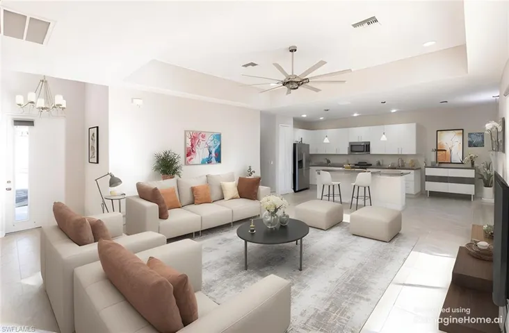 Living room with light tile patterned flooring, sink, ceiling fan with notable chandelier, and a tray ceiling