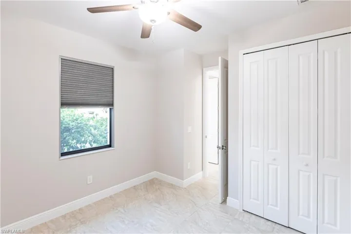 Unfurnished bedroom with ceiling fan and a closet