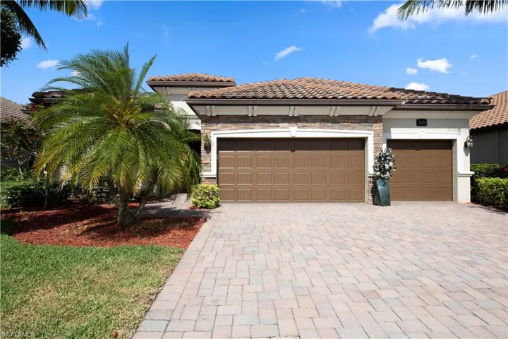 Mediterranean / spanish-style home with decorative driveway, stone siding, an attached 3-car garage, and a tiled roof