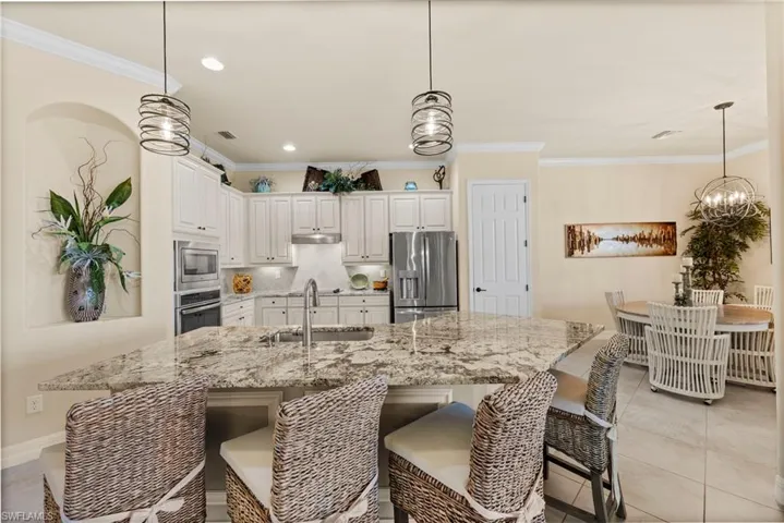 Kitchen featuring stainless steel appliances, ornamental molding, and a sink