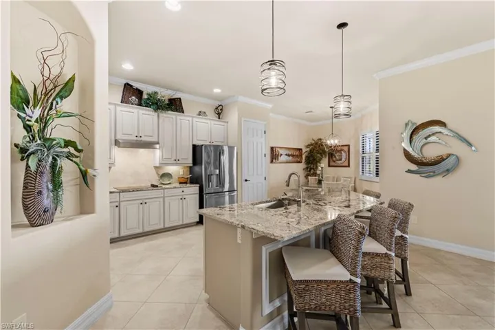 Kitchen with stainless steel refrigerator with ice dispenser, under cabinet range hood, light 20" tile flooring, and a sink
