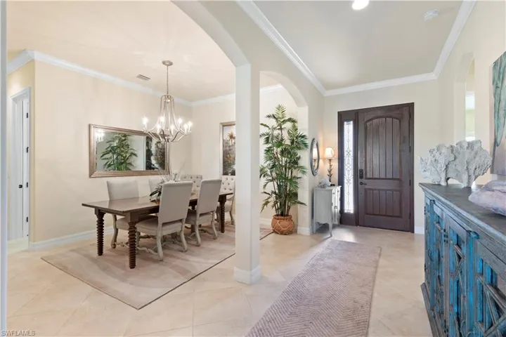 Entryway featuring arched walkways, light tile patterned flooring, ornamental molding, and a notable chandelier