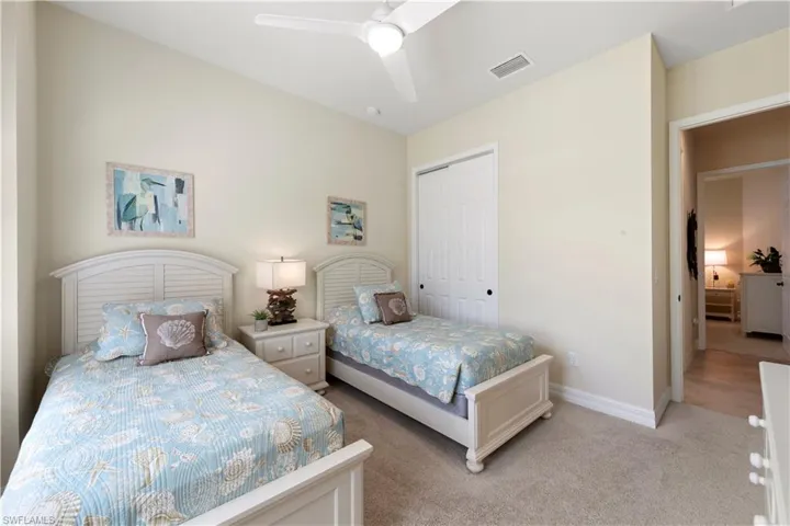 Bedroom featuring a closet, light carpet, baseboards, and a ceiling fan