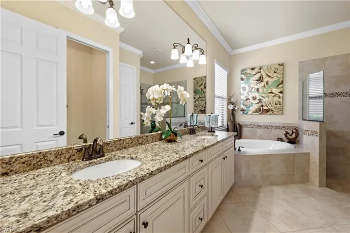 Bathroom with tile patterned floors, double vanity, ornamental molding, a bath, walk-in shower double sinks