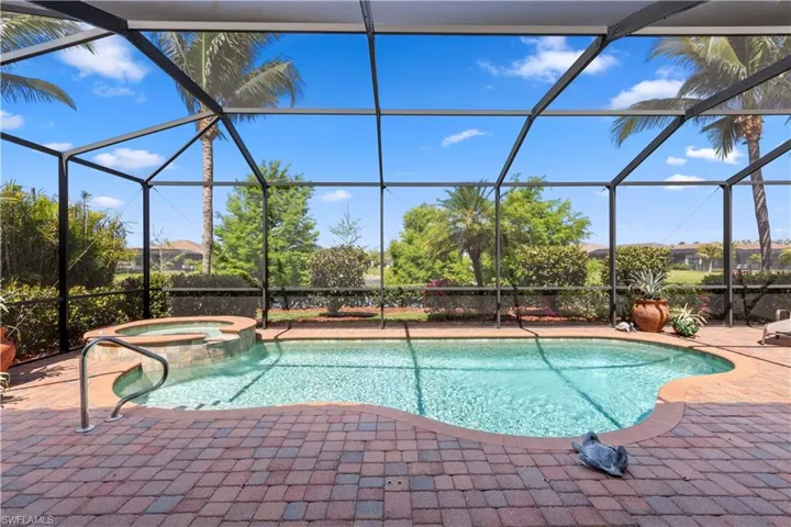 View of swimming pool with a patio, glass enclosure, and a pool with connected hot tub