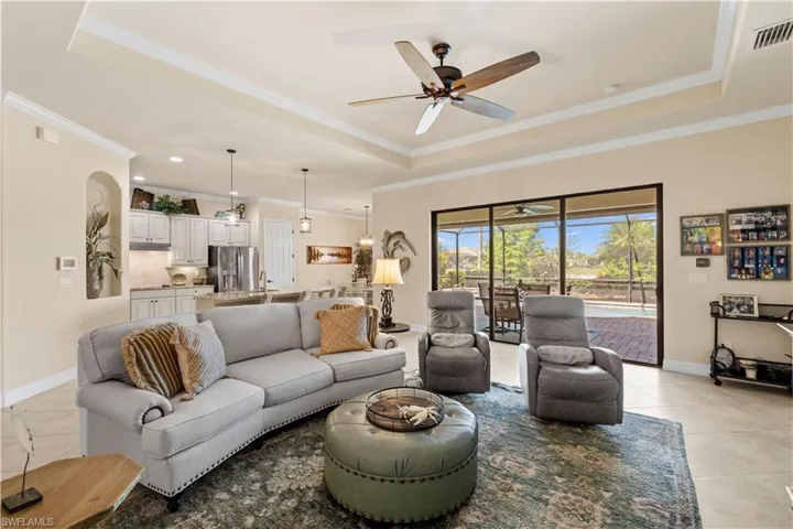 Living area featuring crown molding, ceiling fan, a tray ceiling, and light 20" tile flooring