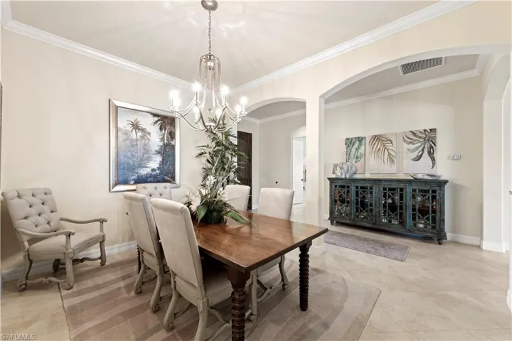 Dining room featuring ornamental molding, a notable chandelier, and arched walkways