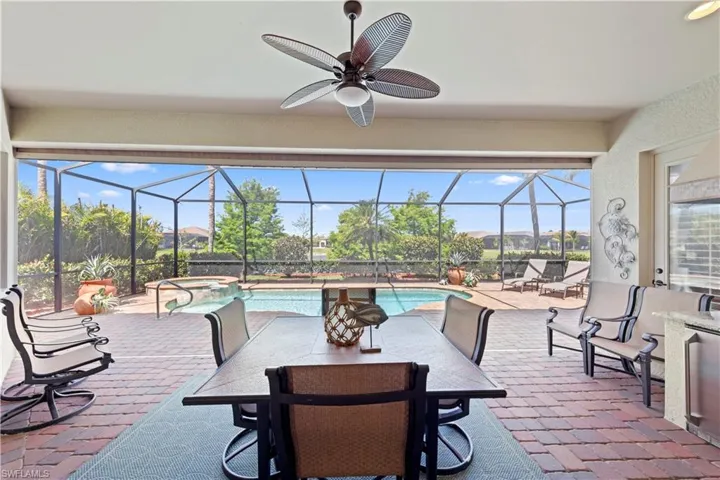 View of patio / terrace with a ceiling fan, outdoor dining space, a pool with connected hot tub, and a lanai
