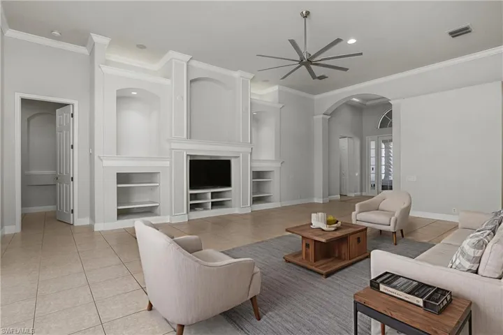 Great Room with view of entertainment wall and door to left leading to master bedroom suite. Ceramic tile flooring. Neutral paint and tile colors.
