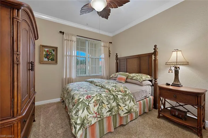 Bedroom with light carpet, crown molding, and a ceiling fan