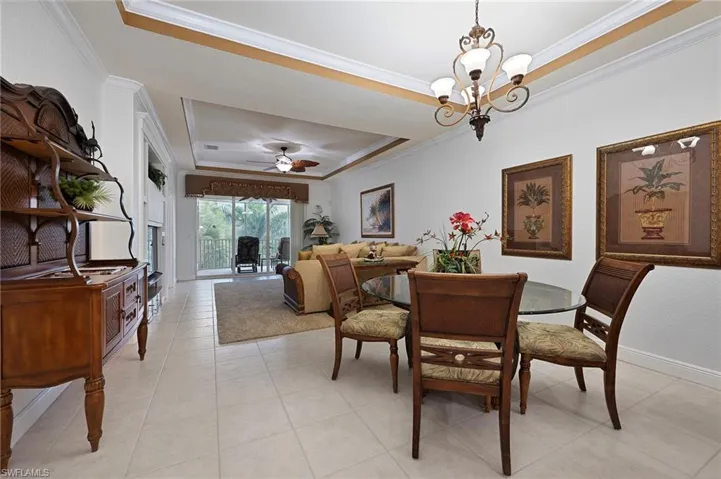 Dining space featuring a raised ceiling, ornamental molding, ceiling fan, and a chandelier