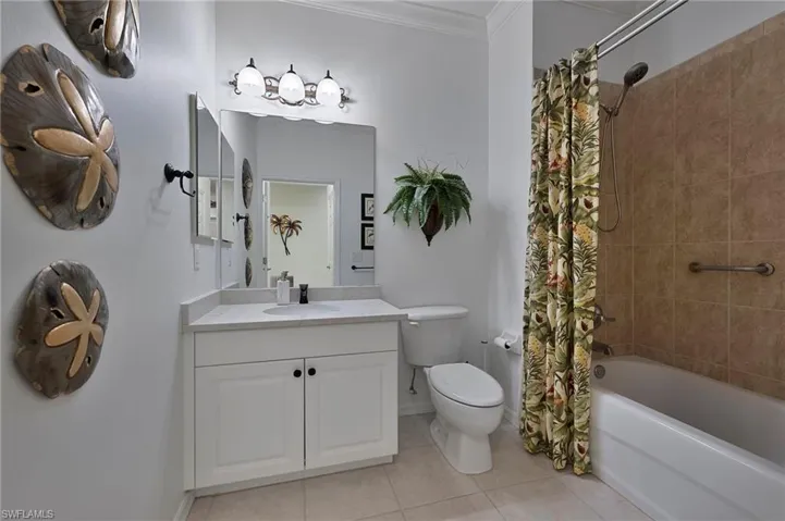 Full bath featuring vanity, tile patterned floors, ornamental molding, and shower / bath combination with curtain