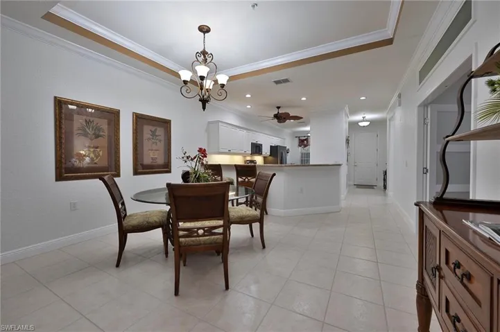 Dining room featuring crown molding, light tile patterned flooring, a chandelier, and a ceiling fan